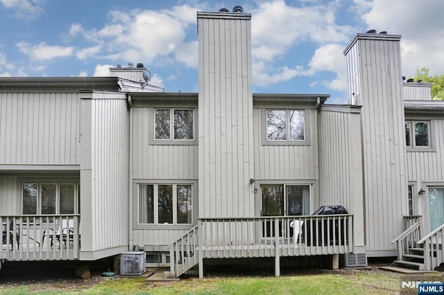 rear view of property with a deck, central AC unit, and a chimney
