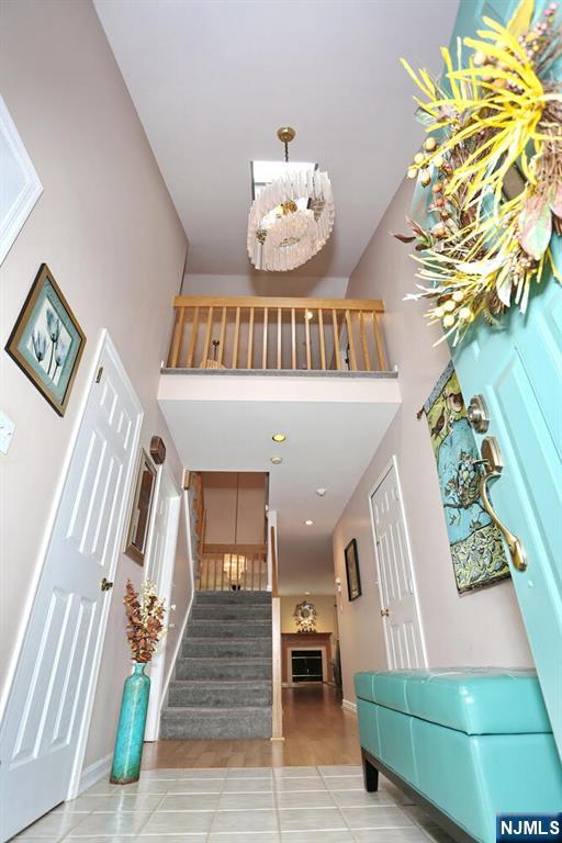 entrance foyer featuring tile patterned floors, baseboards, stairs, and a high ceiling