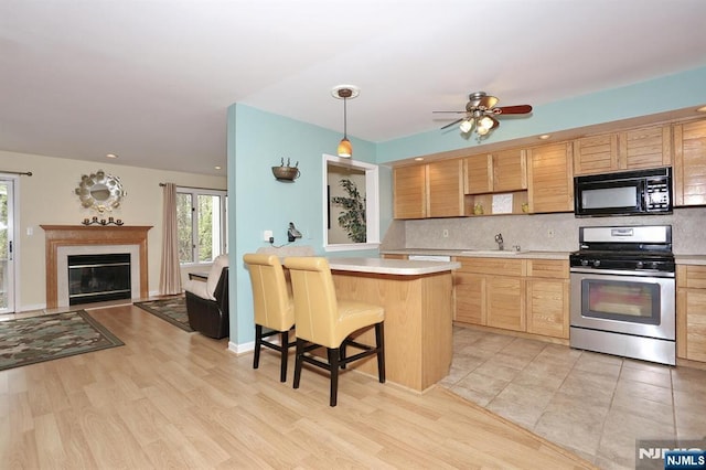 kitchen with tasteful backsplash, a sink, black microwave, light countertops, and gas stove