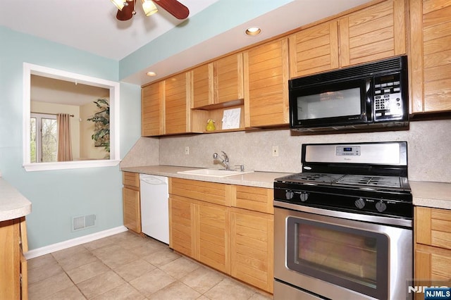 kitchen featuring a sink, black microwave, light countertops, white dishwasher, and gas stove