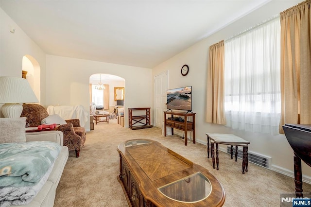 living room with arched walkways, visible vents, and light carpet
