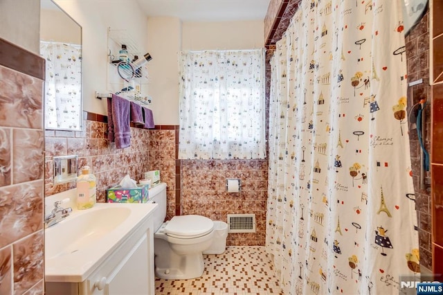 bathroom featuring curtained shower, visible vents, toilet, tile walls, and vanity
