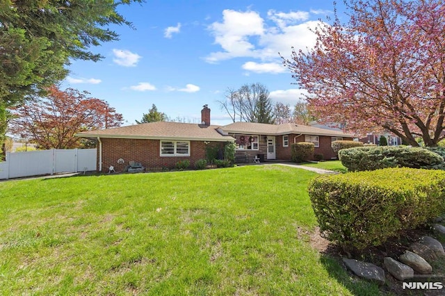 back of property featuring a chimney, brick siding, fence, and a yard