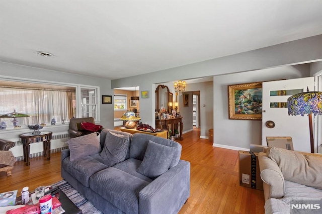 living area featuring radiator, a notable chandelier, baseboards, and light wood-style floors