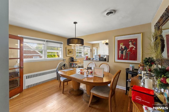 dining room featuring an inviting chandelier, radiator heating unit, visible vents, and light wood-style flooring