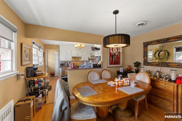 dining room featuring an inviting chandelier, visible vents, and light wood-style flooring