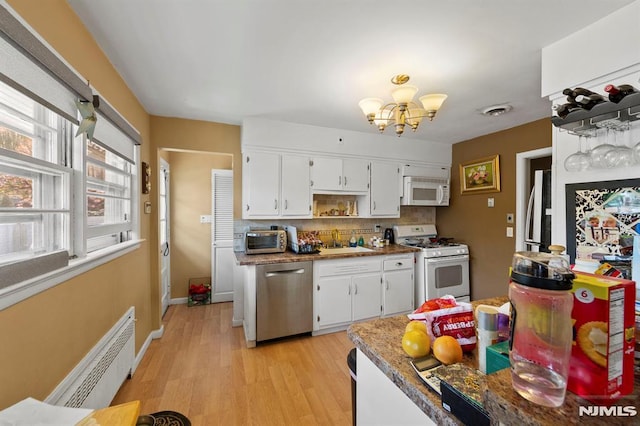 kitchen with white appliances, a chandelier, radiator heating unit, backsplash, and a sink