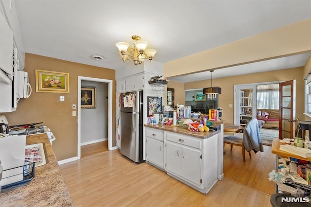 kitchen featuring light wood finished floors, a peninsula, a notable chandelier, and freestanding refrigerator