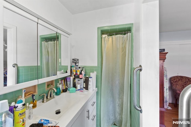 full bathroom with tile walls, curtained shower, wood finished floors, and vanity
