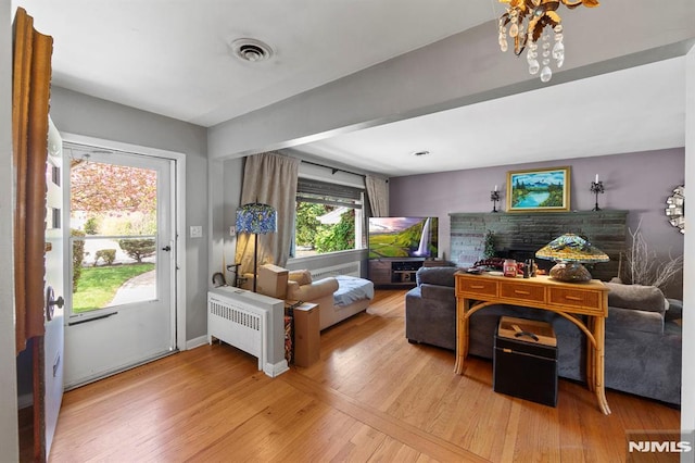 living room featuring visible vents, radiator heating unit, wood finished floors, and baseboards