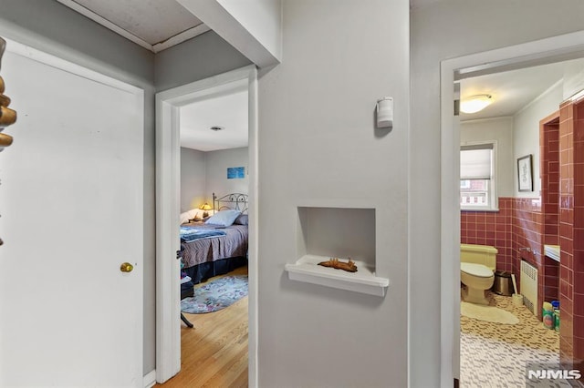 hall featuring tile walls, radiator, a wainscoted wall, and wood finished floors