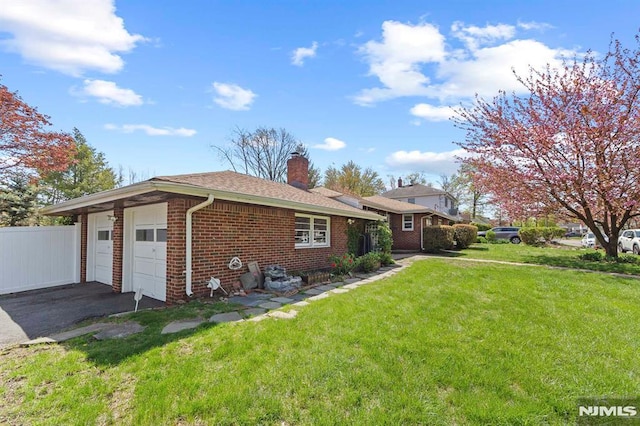 view of property exterior featuring driveway, a chimney, an attached garage, a yard, and brick siding