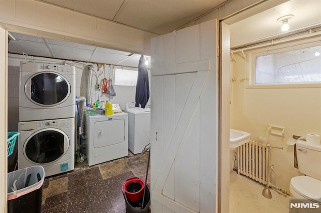 laundry area with stacked washer / drying machine, washer and dryer, laundry area, and radiator