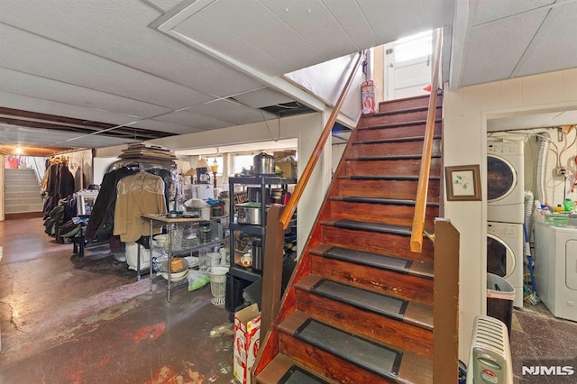 finished basement with stairway and stacked washer and dryer