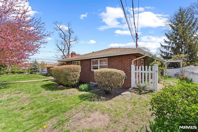 view of property exterior featuring fence, a yard, a chimney, and brick siding