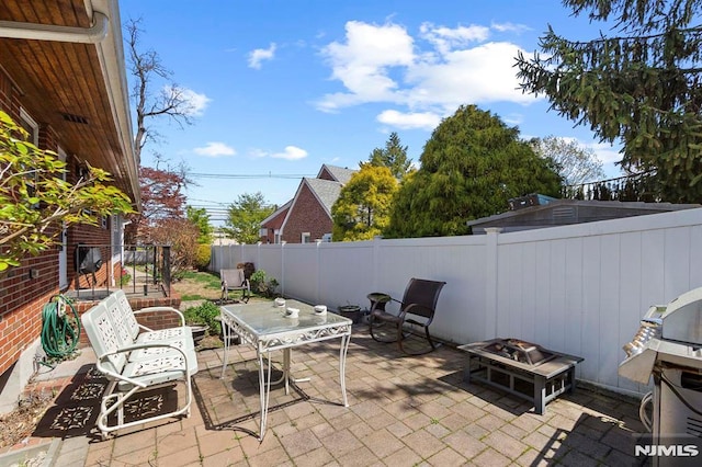view of patio featuring a grill, an outdoor fire pit, a fenced backyard, and outdoor dining space