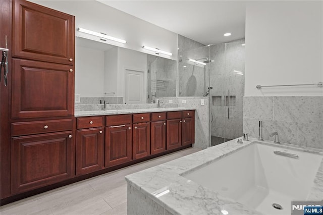 bathroom with a sink, a stall shower, double vanity, and a bath