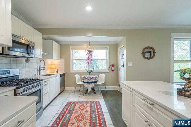 kitchen featuring a sink, white cabinets, stainless steel appliances, and light countertops