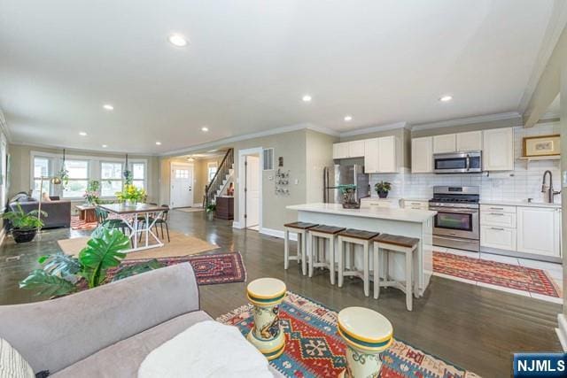 living area featuring baseboards, recessed lighting, stairway, and crown molding