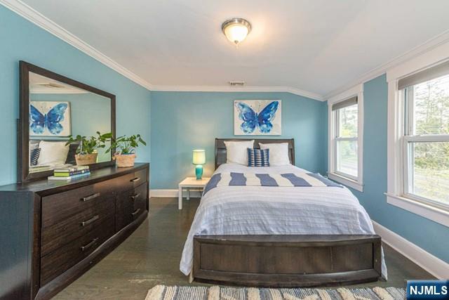 bedroom with ornamental molding, dark wood-style floors, and baseboards