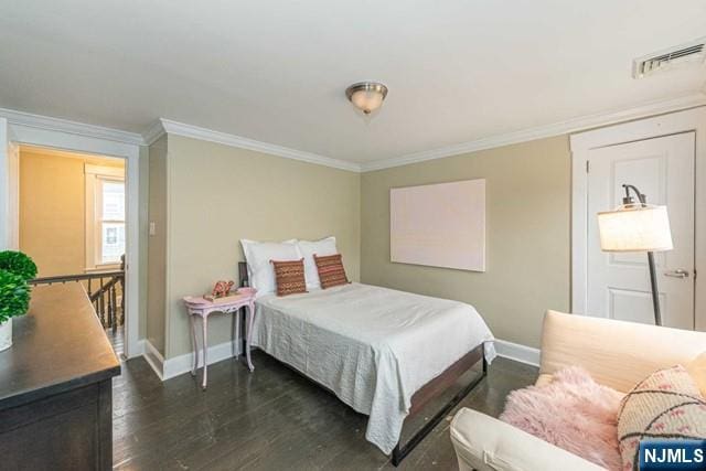 bedroom featuring baseboards, visible vents, dark wood finished floors, and crown molding