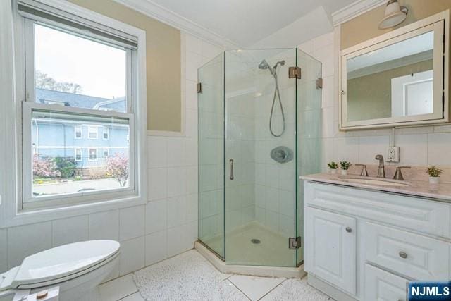 full bathroom with vanity, crown molding, a stall shower, and tile walls