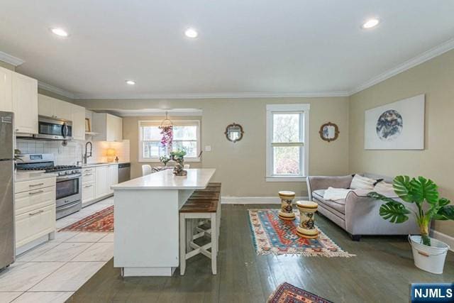 kitchen with appliances with stainless steel finishes, plenty of natural light, ornamental molding, and light countertops
