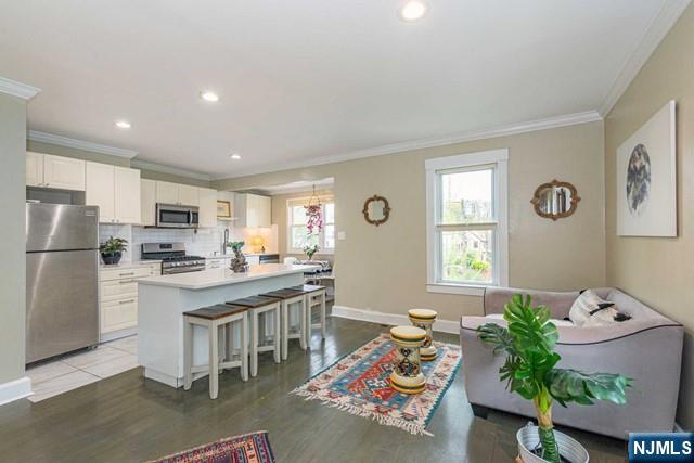 living room with crown molding, recessed lighting, light wood-style flooring, and baseboards