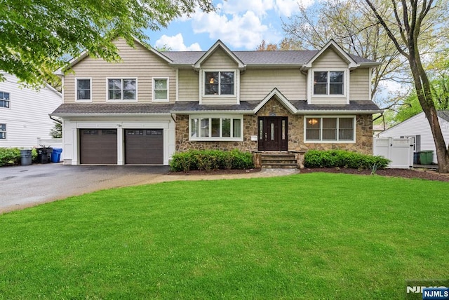 view of front of home with fence, a garage, driveway, stone siding, and a front yard