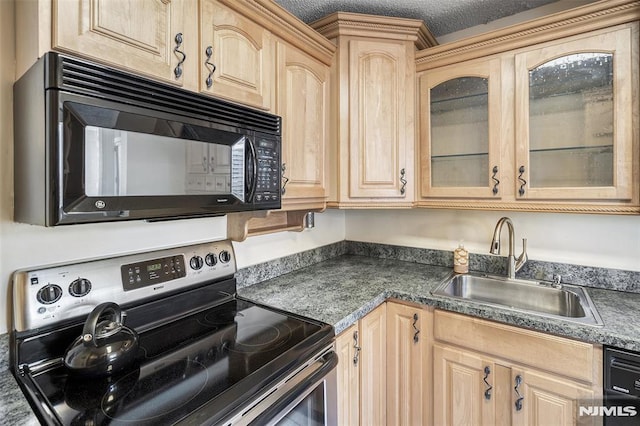 kitchen with light brown cabinetry, dark countertops, glass insert cabinets, a sink, and black appliances