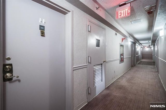 corridor with carpet, a textured ceiling, and visible vents