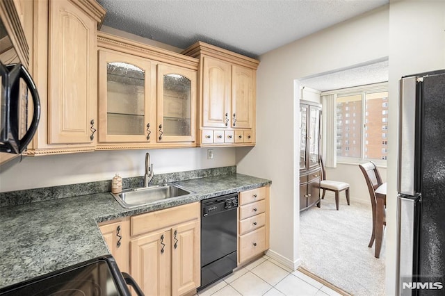 kitchen with a sink, light brown cabinetry, black appliances, and dark countertops