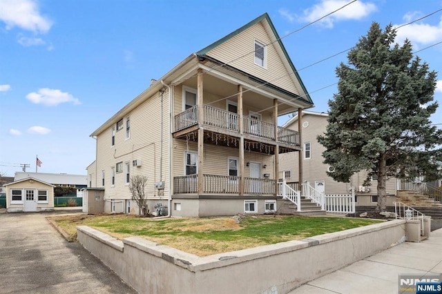 exterior space featuring stairs, a front lawn, and a balcony
