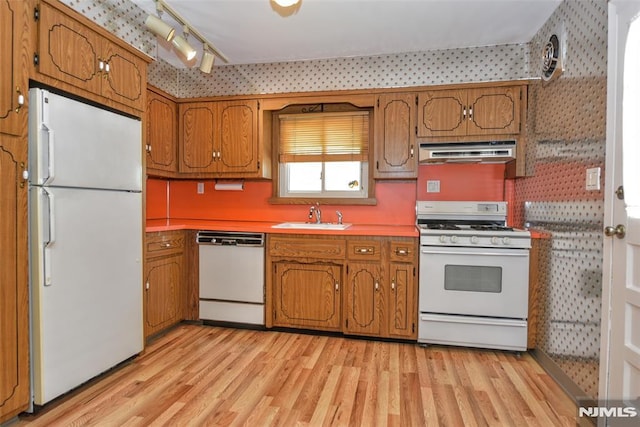 kitchen featuring a sink, light wood-style floors, white appliances, brown cabinetry, and range hood