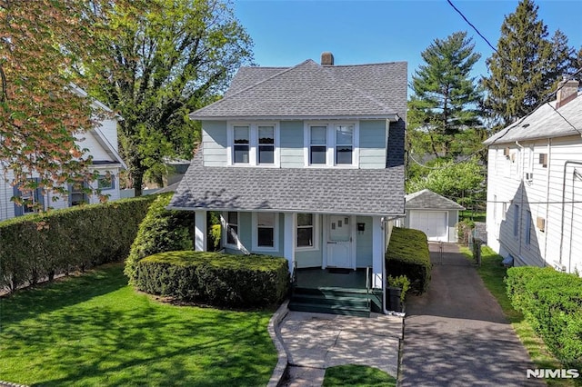 view of front of house with roof with shingles, a garage, a porch, an outbuilding, and a chimney