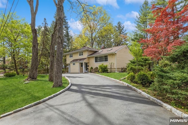tri-level home with a chimney, driveway, and a front yard
