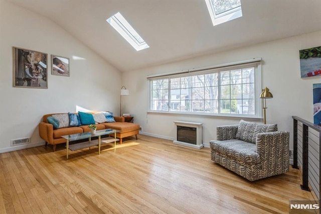 living room with vaulted ceiling with skylight, baseboards, wood finished floors, and visible vents