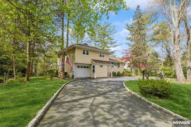 view of side of property with a yard, a garage, and aphalt driveway