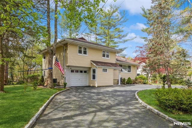 view of front of house featuring driveway, a front lawn, and a garage