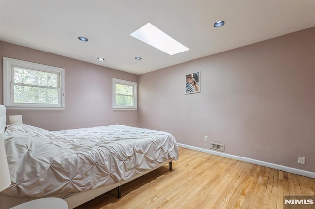 bedroom featuring recessed lighting, baseboards, wood finished floors, a skylight, and visible vents