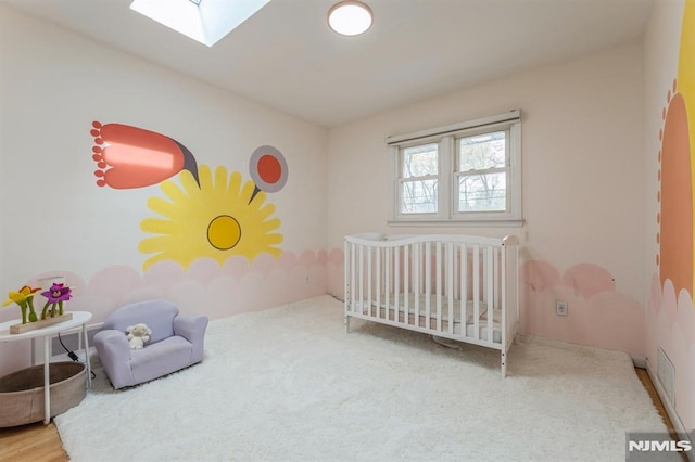 carpeted bedroom with a nursery area and a skylight