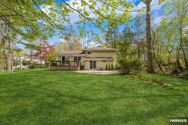 back of property with a yard, a deck, and a patio