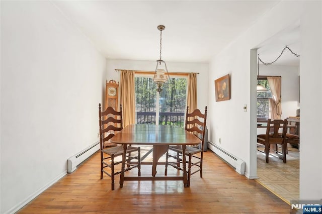 dining area with plenty of natural light, a baseboard radiator, and light wood-type flooring