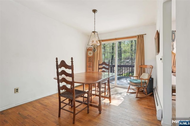 dining area featuring baseboards, a baseboard heating unit, and hardwood / wood-style floors