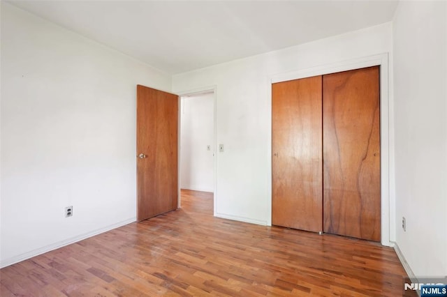 unfurnished bedroom featuring baseboards, a closet, and wood finished floors