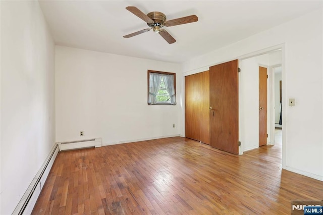 unfurnished room with baseboards, ceiling fan, a baseboard heating unit, and light wood-style flooring