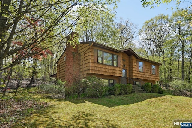 exterior space featuring a lawn, an attached garage, and a chimney