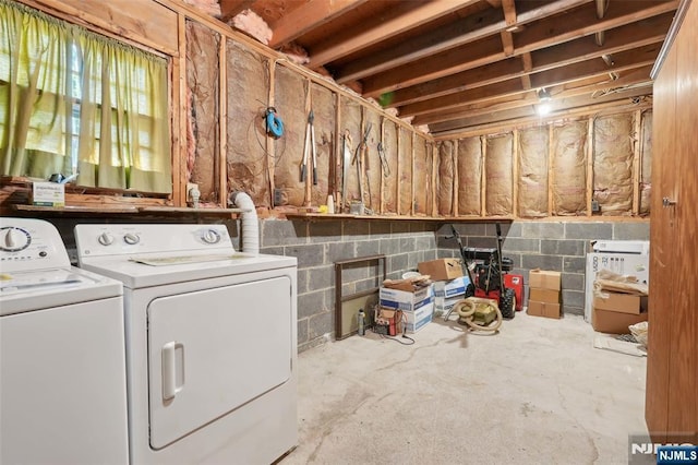 washroom featuring concrete block wall, separate washer and dryer, and laundry area