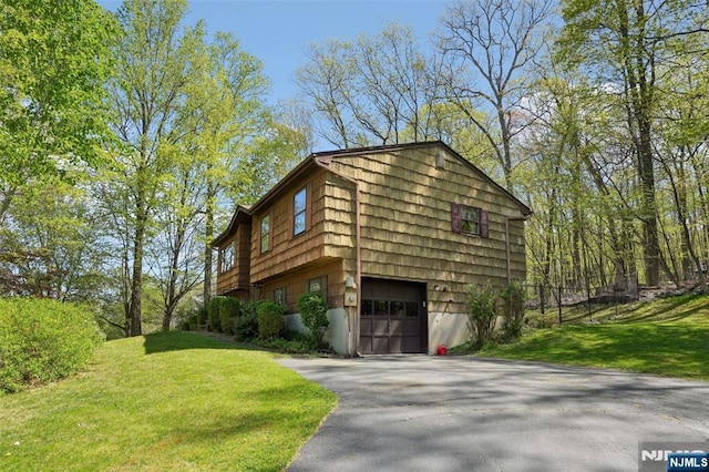 view of property exterior with a garage, a yard, and driveway