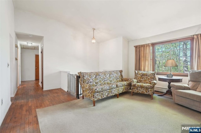 living area with a baseboard radiator, wood-type flooring, and attic access